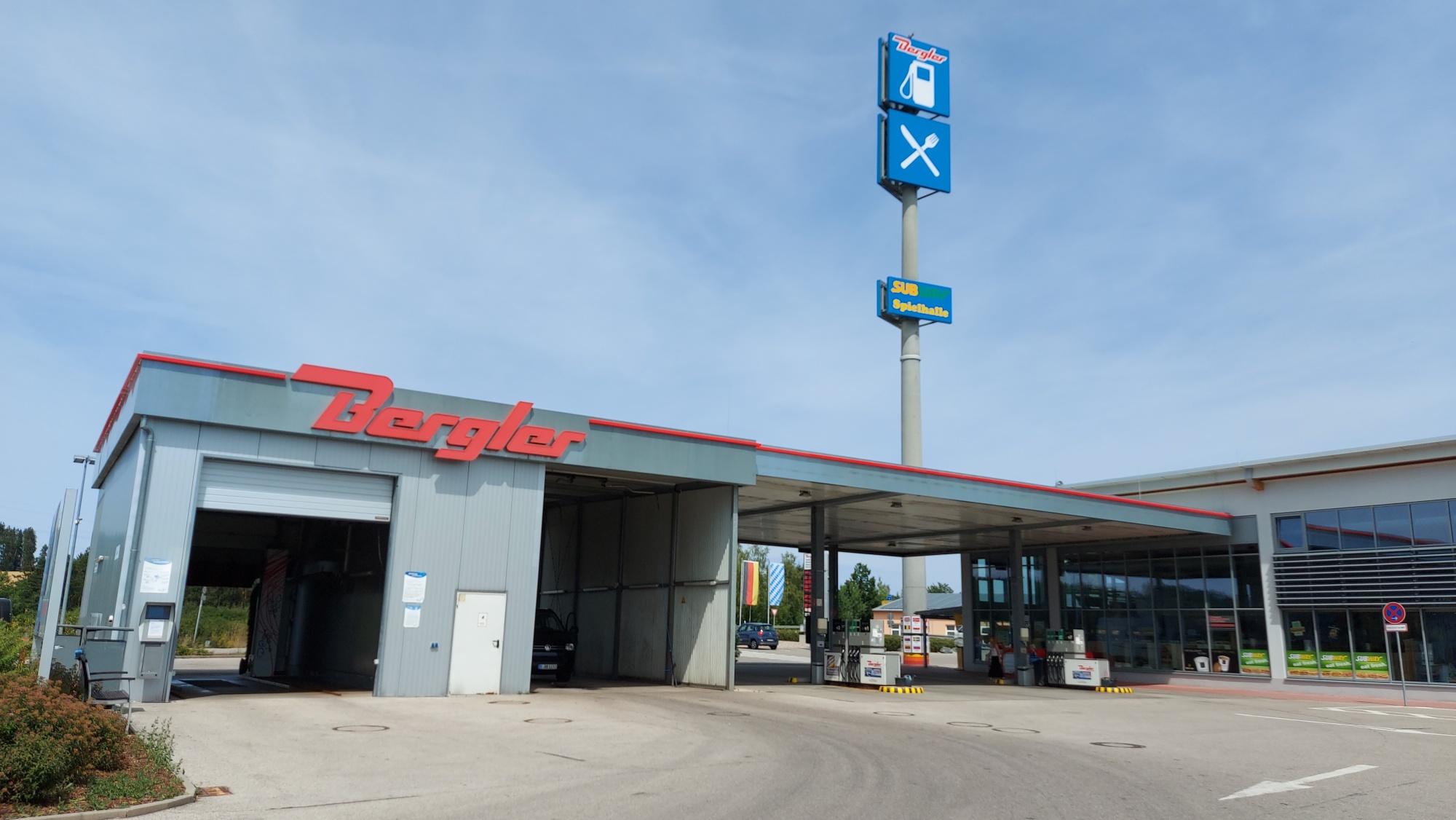 Links im Bild die SB-Waschbox und Waschanlage. Über dem Gebäude das rote Bergler Logo. Angrenzend ist der Tankplatz des Autohofes.