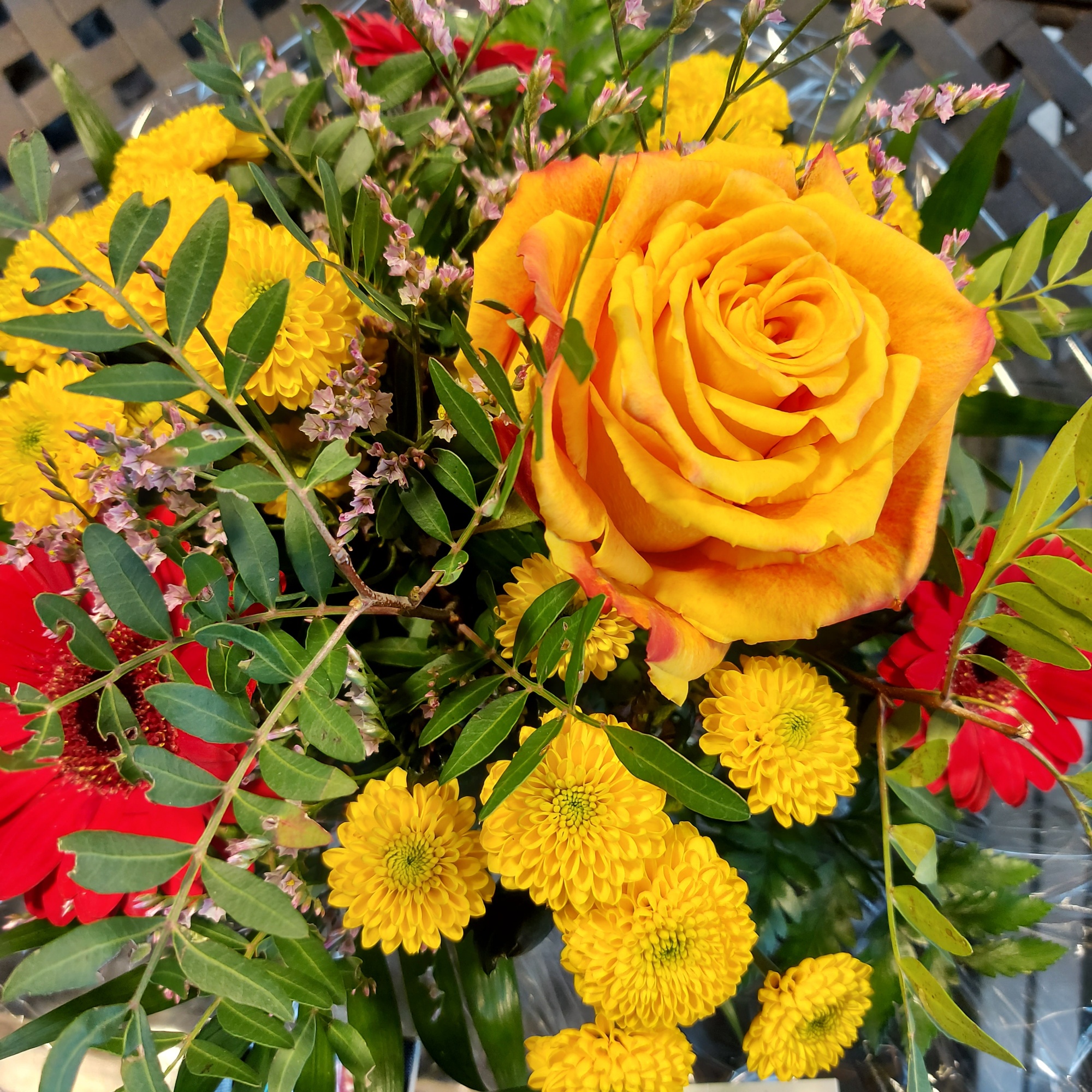 Eine gelbe Rose blitzt aus einem Blumenstrauß hervor, der im Eingangsbereich am Autohof Bergler steht.