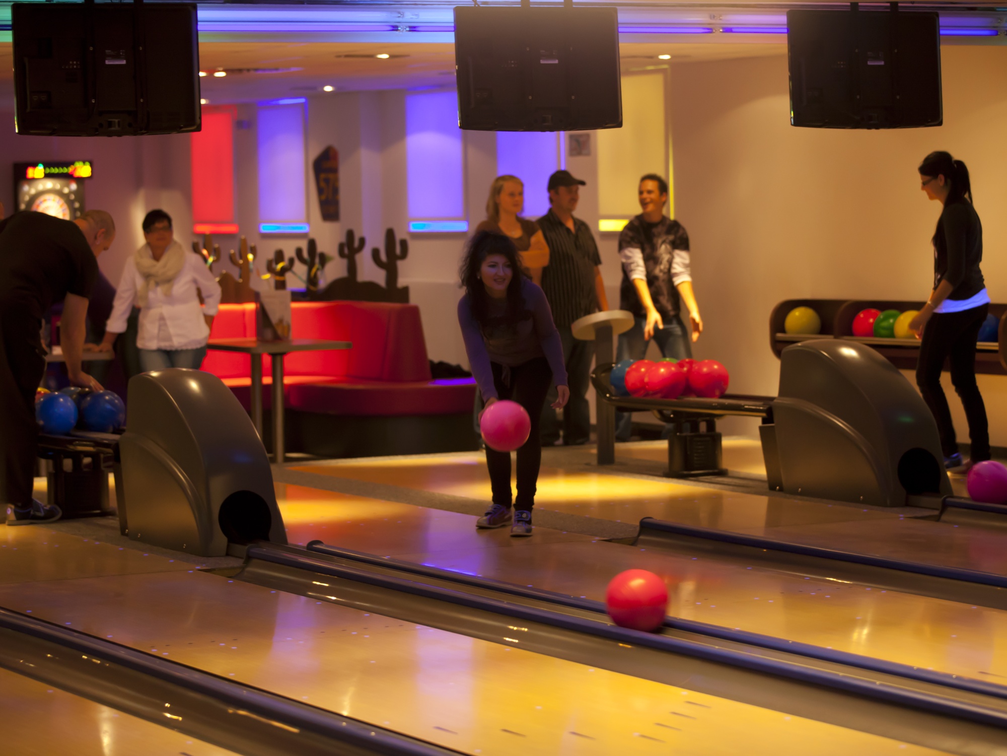 Eine Gruppe von Personen, die gerade an den Bahnen Bowling spielen